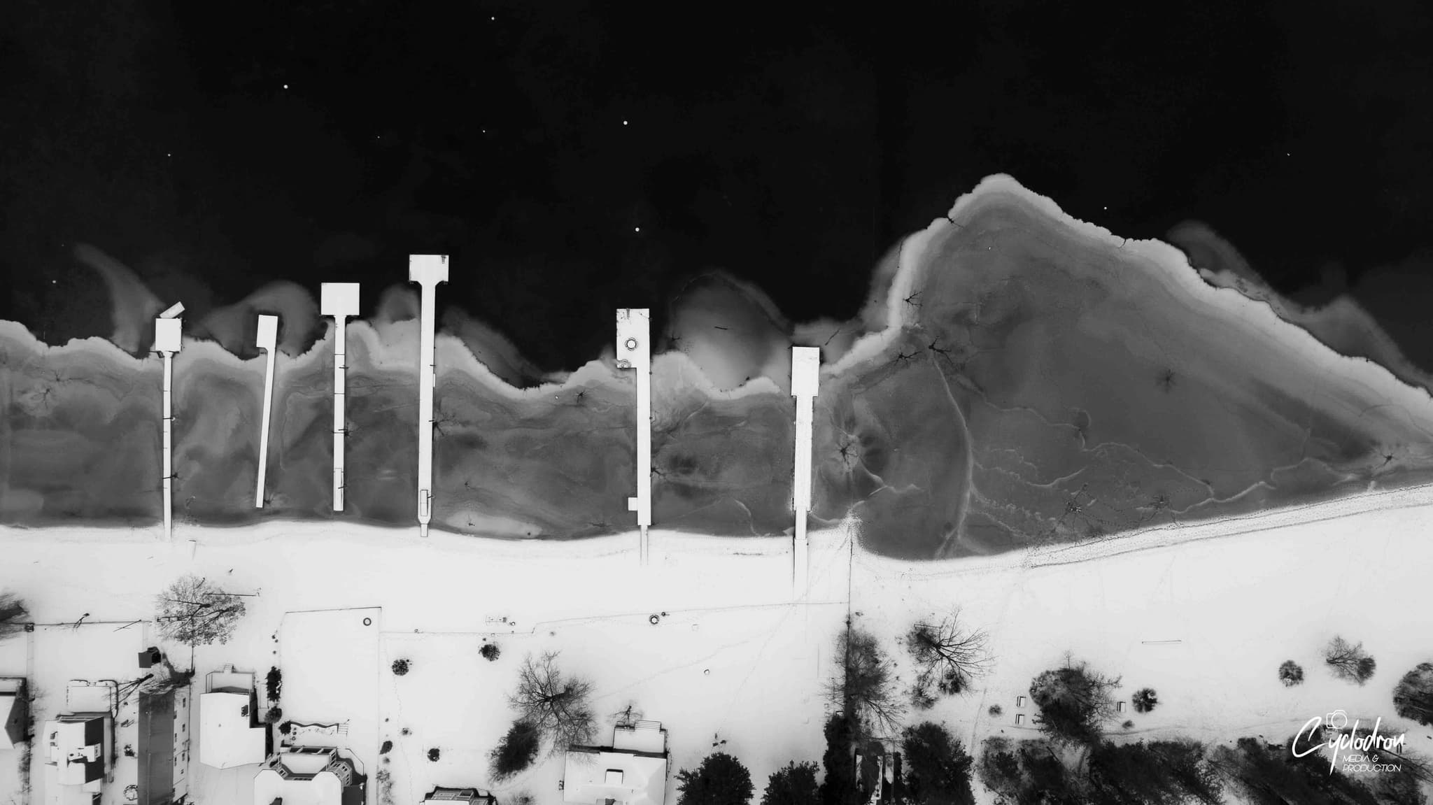 Black and white aerial artistic composition with inverted clouds and posts