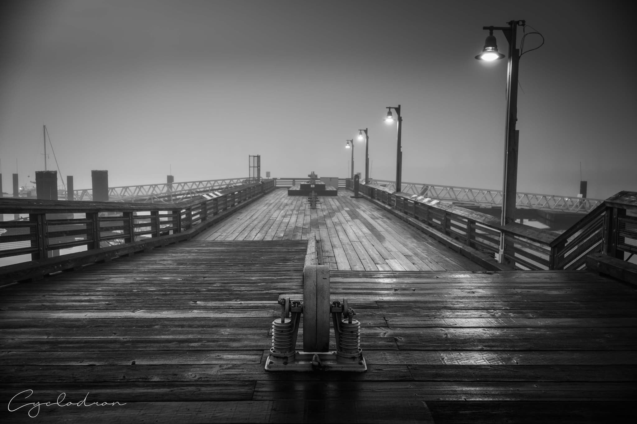 Black and white wooden pier extending into foggy atmosphere