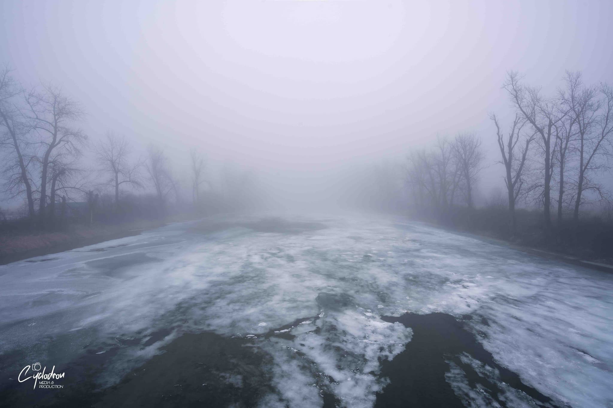 Frozen river with ice patterns and atmospheric fog