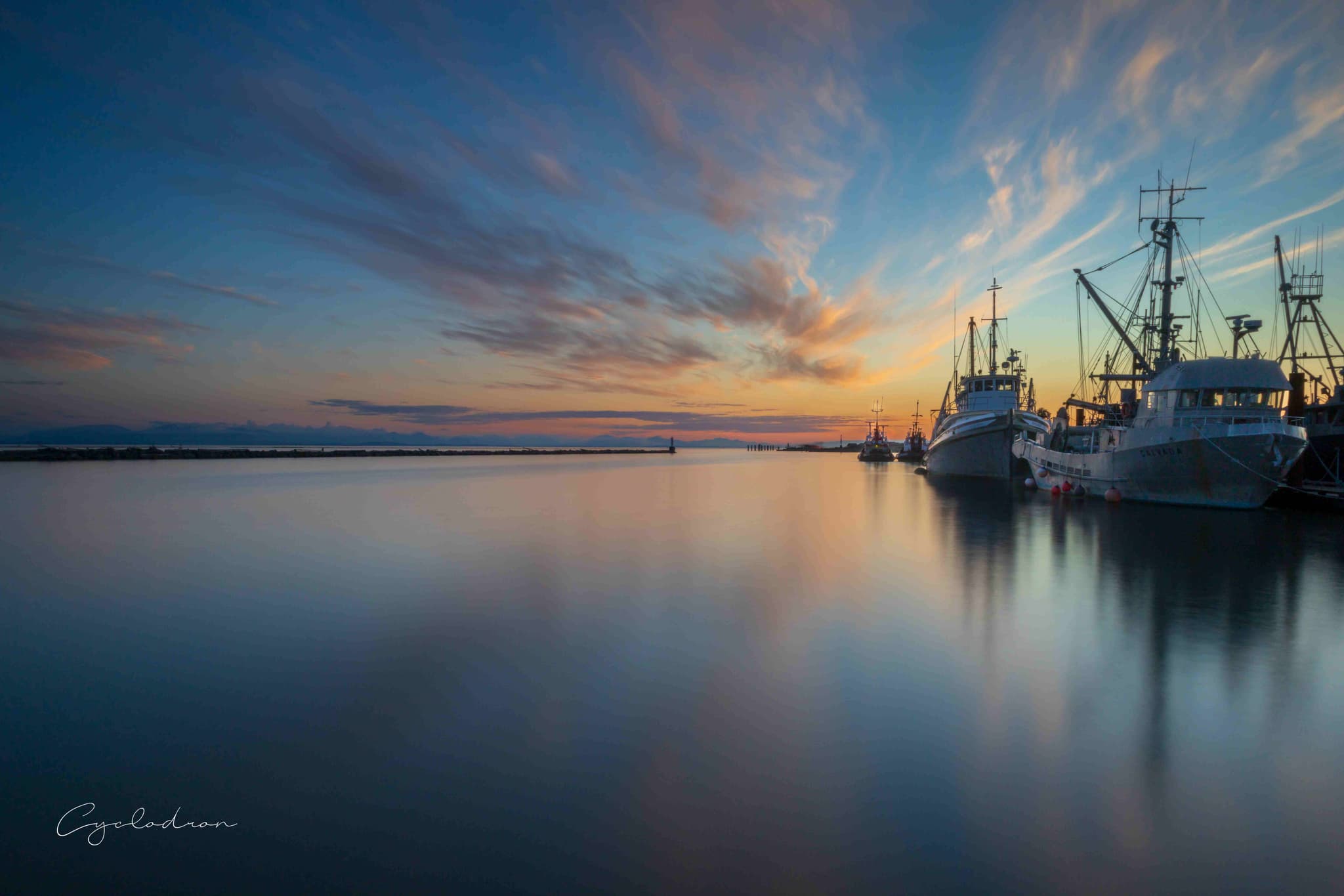 Harbor sunset with fishing boats and dramatic wispy clouds
